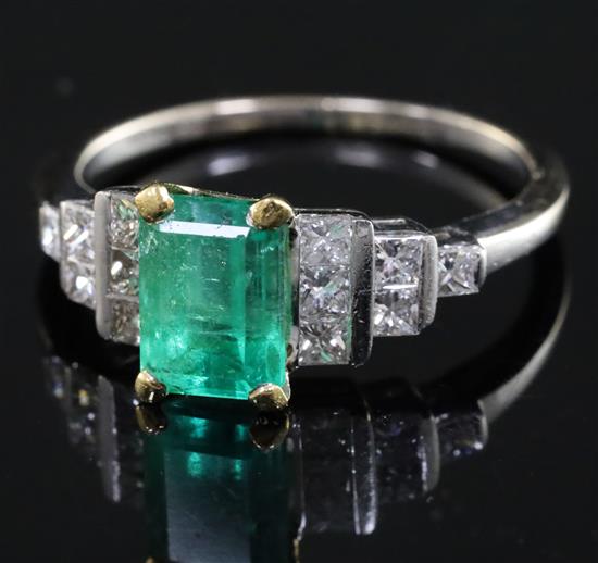 An 18ct white gold and single stone emerald ring with stepped princess cut diamond set shoulders, size R.
